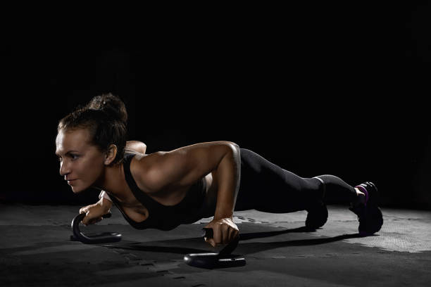 istock Female athletes with holders doing push-ups in gym in darkness 1351835226