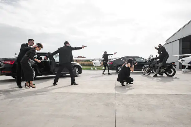 Tactical exercise training. An armed bodyguard security team protects a celebrity vip person in danger combat situation when attacked. Security police team in civilian black suit with sunglasses