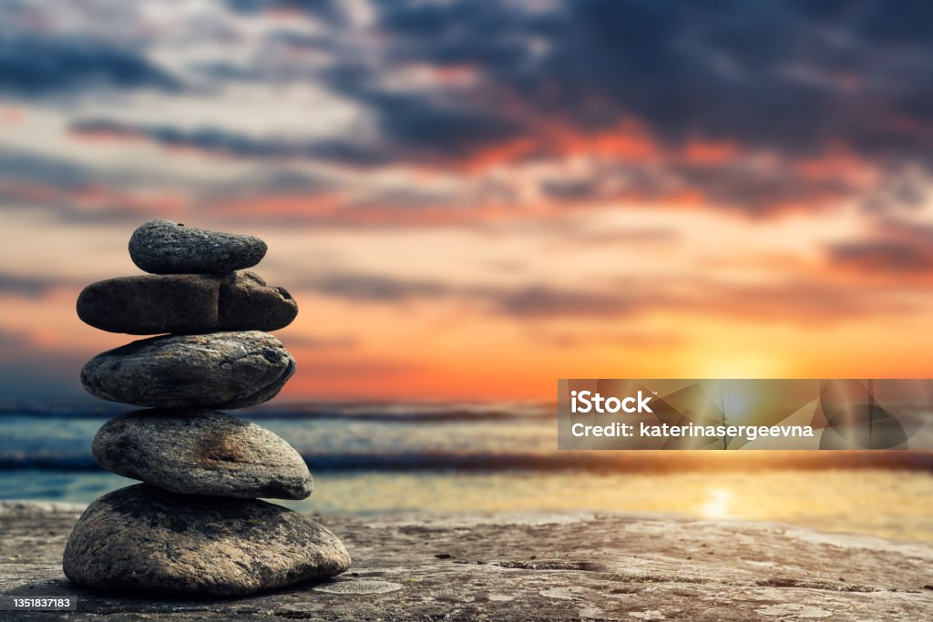 Zen pyramid of stones on the background of sunset and sea Zen-like Stock Photo