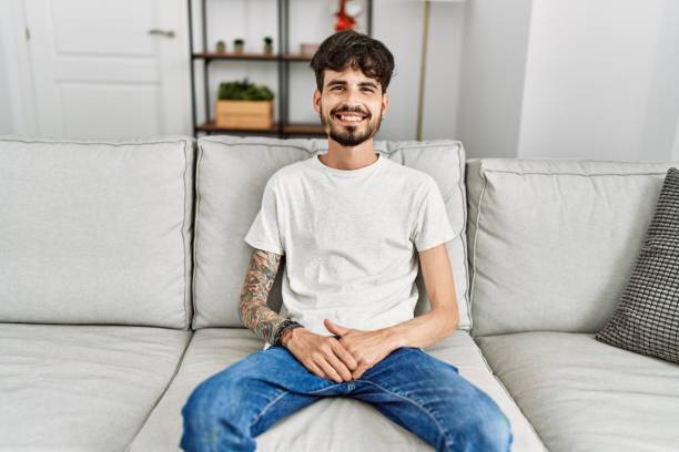 istock Young hispanic man smiling happy sitting on the sofa at home. 1351837961