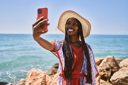 Young african american woman smiling happy make selfie by the smartphone at the beach.