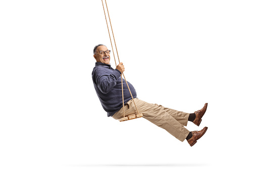 Full length side shot of a happy mature man swinging on a swing isolated on white background
