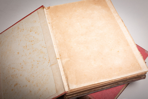 An old book with a red cover with a blank page open.
