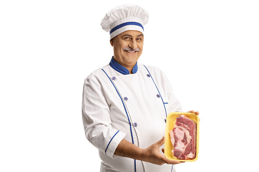 Mature male chef holding a packed raw steak isolated on white background