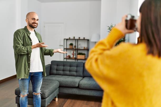 istock Young hispanic woman make photo using camera to man at home. 1351844415