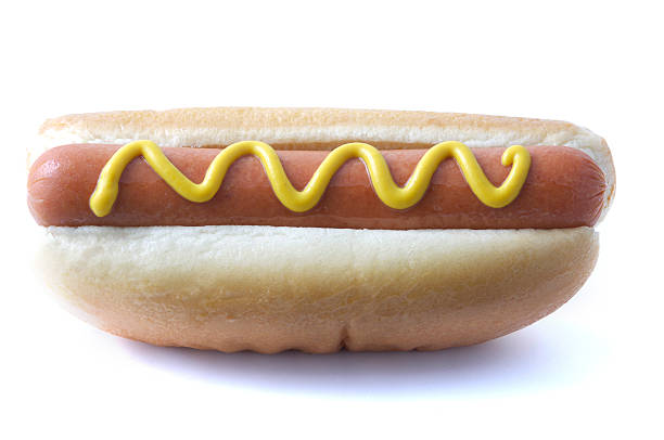 Hot dog wiener topped with yellow mustard on a white bun stock photo