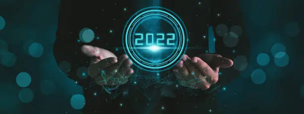 Photo of Businessman hand holding 2022 number,happy new year concept digital trends,industry and business trend of world full modernity advanced technology,artificial intelligence or AI,banner header panoramic