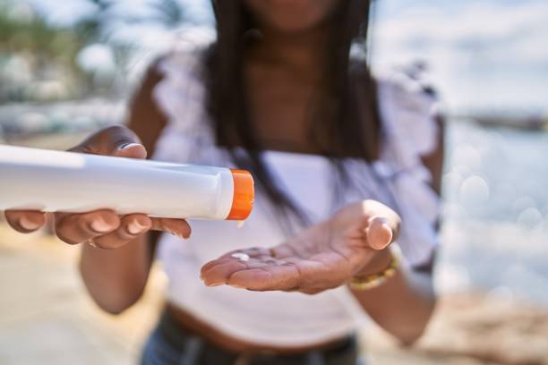 Young african american girl using sunscreen lotion at the beach.