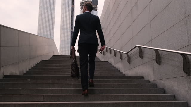 Businessman going up the stairs. camera moves up. Climbing the steps to success