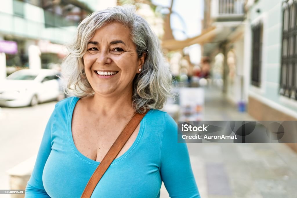 Middle age grey-haired woman smiling happy standing at the city. Mature Women Stock Photo