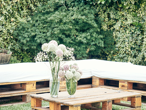 Table made with wooden pallets decorated with a vase with flowers, wedding decoration concept