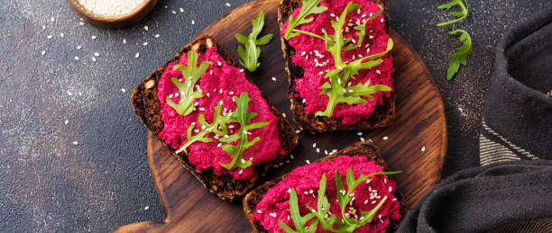 istock Bruschetta with beetroot hummus, arugula and sesame seeds on dark concrete background. Top view 1351851157