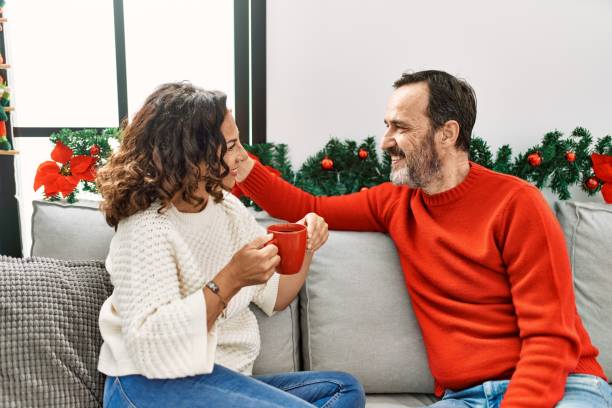 istock Middle age hispanic couple drinking coffee sitting on the sofa at home. 1351852645