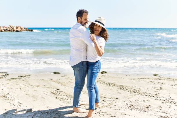 istock Middle age hispanic couple smiling happy dancing at the beach. 1351852681