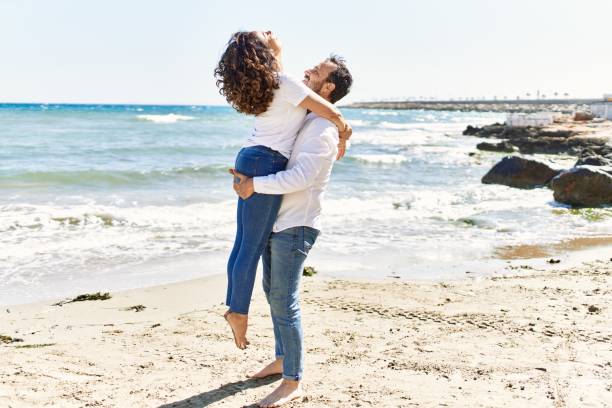 istock Middle age hispanic couple smiling happy and hugging at the beach. 1351852700