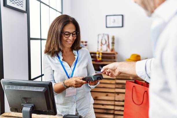 istock Middle age man and woman smiling confident paying using credit card and data phone at clothing store 1351852713