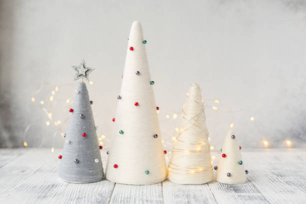 Handmade Christmas trees and garland. Yarn wrapped XMAS cone trees with minimalistic decor. XMAS gifts. DIY concept stock photo