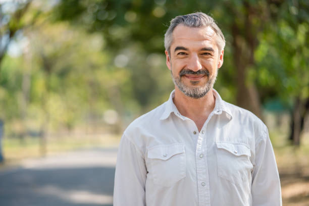 Portrait of senior man smiling and loooking at camera in the park.Retirement relax concept Portrait of senior man smiling and loooking at camera in the park.Retirement relax concept 45 49 years stock pictures, royalty-free photos & images