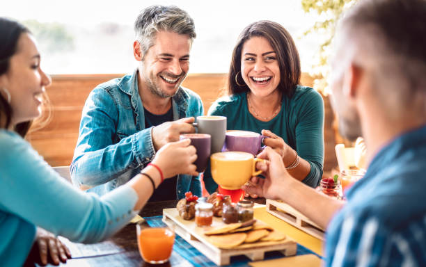 コーヒーバーの屋上でラテを乾杯する人々 - カプチーノレストランで一緒に話したり楽しんで友達 - カフェテラスで幸せな男女とのライフスタイルのコンセプト - 明るい暖かいフィルタ - 友情 ストックフォトと画像