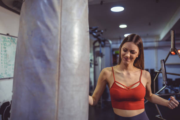 Female boxer hitting a punching bag  at gym. Women training hard Young woman training punch  for punching bag. Girl making Strong kick. gym. weight class stock pictures, royalty-free photos & images