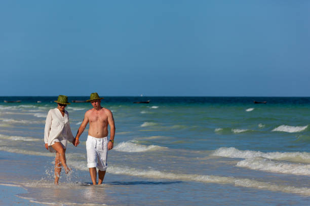 A man and a girl are holding hands walking along the beach in Mombasa Africa