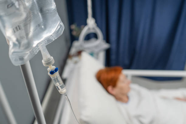Anesthesia for the patient Close-up of iv drip hanging above the bed with patient in the hospital ward saline drip stock pictures, royalty-free photos & images