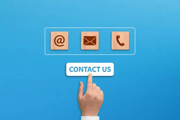 Contact us concept, wooden blocks with email, mail and telephone icons with hand choosing on blue background