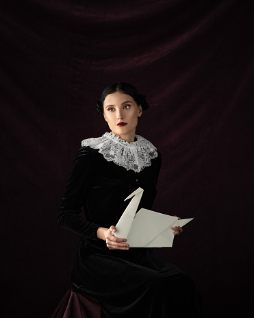 Studio portrait of young woman with object in hands on black background