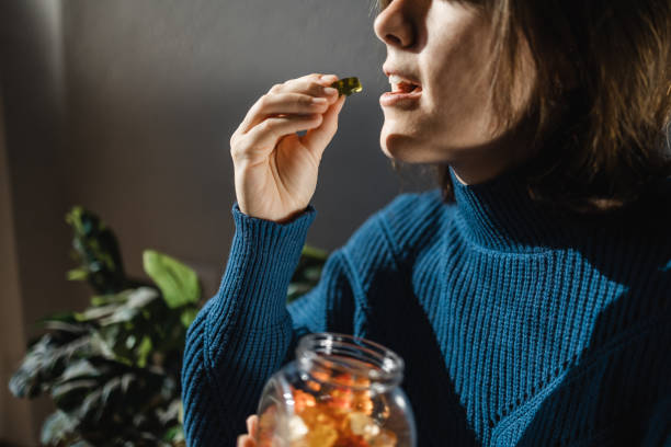 cbd cannabis gummy - mujer que come hierba comestible hoja de caramelo dulce para el tratamiento alternativo de la ansiedad - marihuana medicinal - take treatment fotografías e imágenes de stock