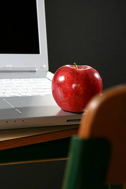 istock School classroom. Education. Red apple on laptop computer at desk. 135187482