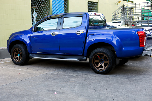 Blue colored Isuzu Highlander pick-up truck parked in street in front of house in Bangkok