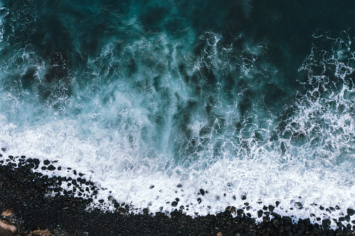 Aerial view of ocean waves breaking on rocky beach