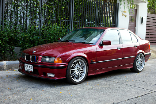 Bordeaux colored BMW 325 parked in street of Bangkok