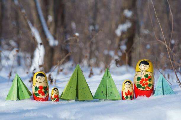istock A row of nesting dolls and toy Christmas trees in a snowy forest. 1351884875