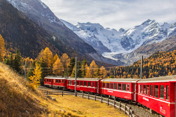 a red passenger train with bernina massif and morteratsch glacier - engadine switzerland mountain snow imagens e fotografias de stock