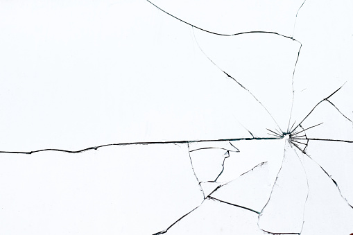 Bullet hole in broken glass on a white background. Shards of glass