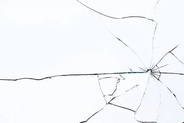 Photo of Bullet hole in broken glass on a white background. Shards of glass