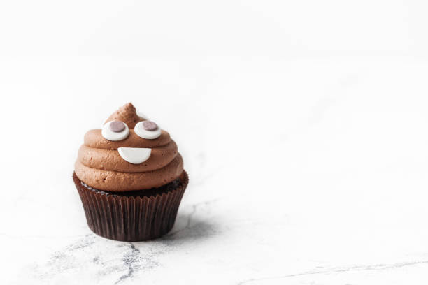 istock Chocolate cupcake with brown cream cheese top decorated with mastic smiley face. 1351888692