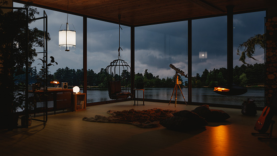 Interior of a modern cozy lake house with fireplace and indoor plants in evening.