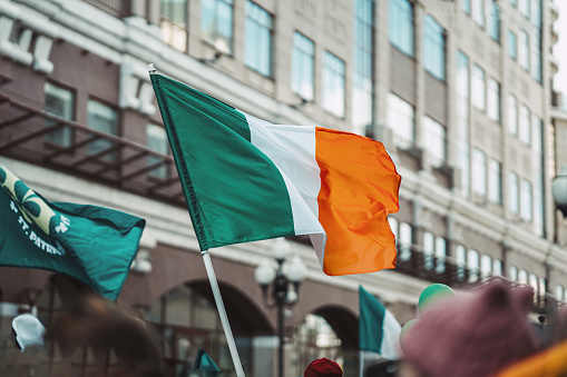 National Flag of Ireland close-up above people crowd, traditional carnival of St. Patrick's Day