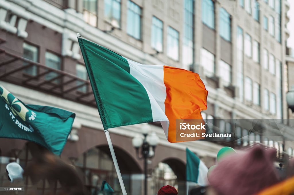 National Flag of Ireland close-up above people crowd, traditional carnival of St. Patrick's Day National Flag of Ireland close-up above people crowd, city street, traditional carnival of St. Patrick's Day St. Patrick's Day Stock Photo