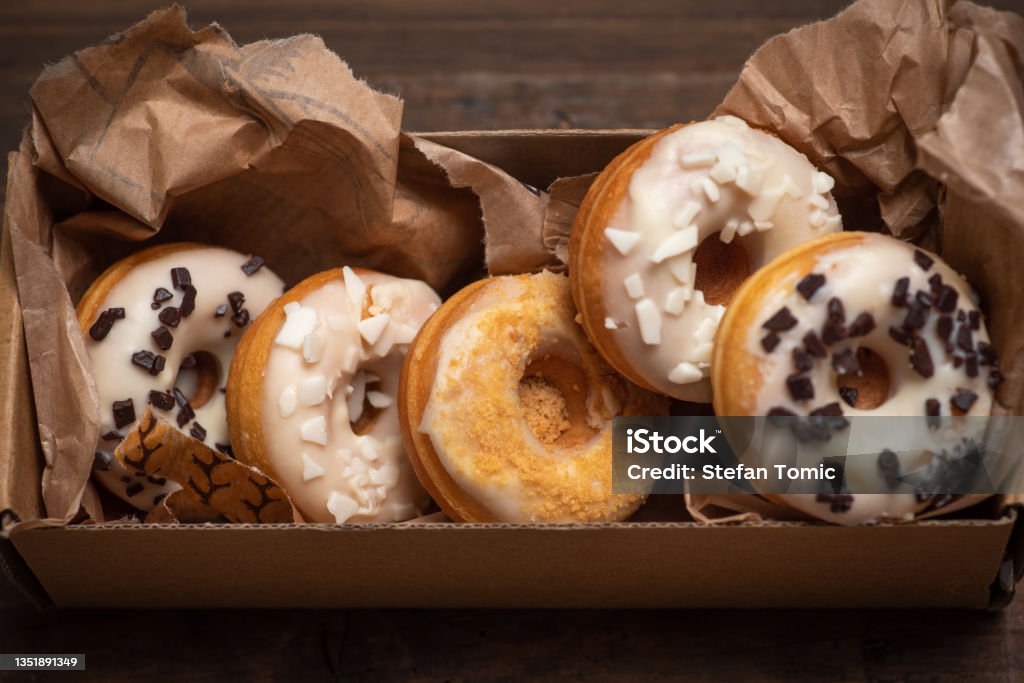 White glazed mini donut in a box White glazed mini donuts in a box. White mini donuts decorated with white and dark chocolate on a wooden background. Delicious, sweet food. Doughnut Stock Photo