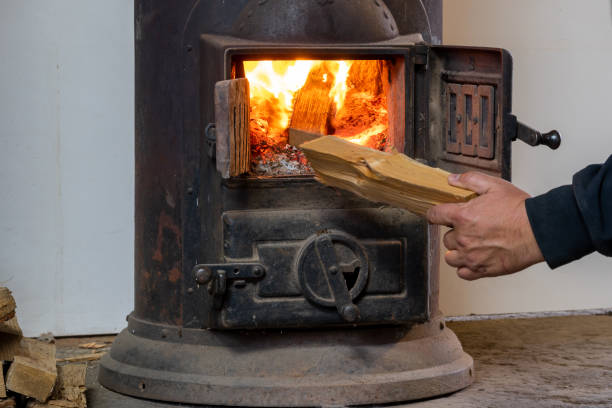 istock Man putting log to wood burning stove 1351891372