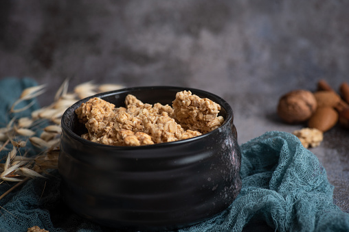 Protein crisp, muesli in a black bowl on a gray-blue decorative background. Healthy protein breakfast.