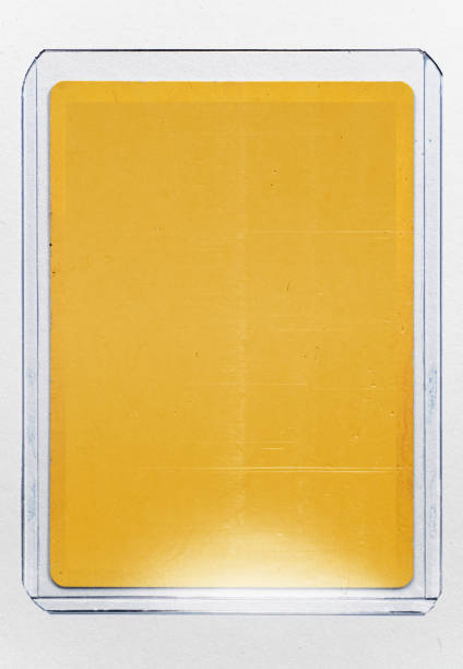 empty yellow trading card with no content or picture behind transparent plastic top loader case on white paper background. stock photo