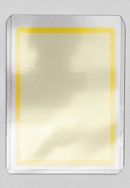 istock blank trading card with yellow border behind transparent plastic top loader case on white paper background. 1351892469