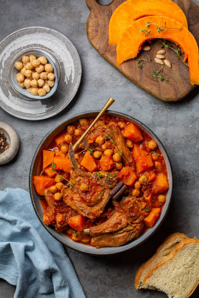 istock Pumpkin, chickpea  and lamb stew with cinnamon sticks. Gray table surface, top view, vertical image. 1351893458