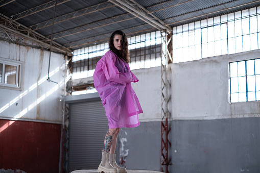 Young woman wearing pink raincoat in abandoned places.