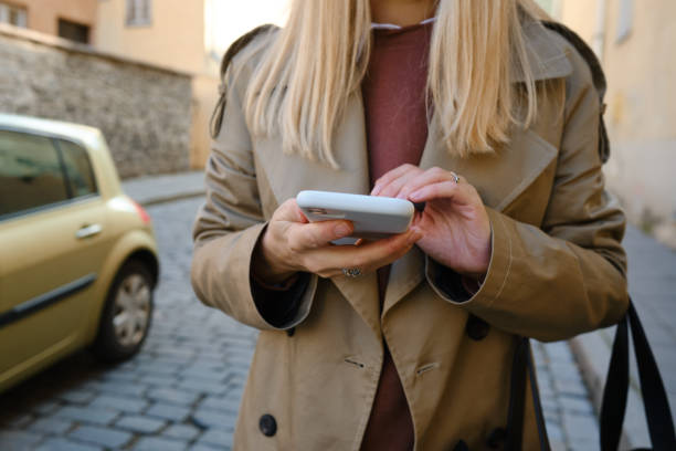 istock Woman is holding a modern smartphone, sending a text message or using an app on her mobile phone. Internet technology user. Smartphone close-up. Focus on the phone screen 1351905877
