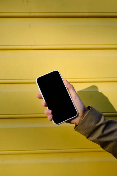 Smartphone close-up on a yellow background. Copy space for your text and informational content on your phone. Focus on the phone screen. Gadget addiction stock photo